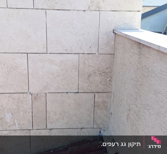 גג רעפים אדום ליד קיר אבן בהיר